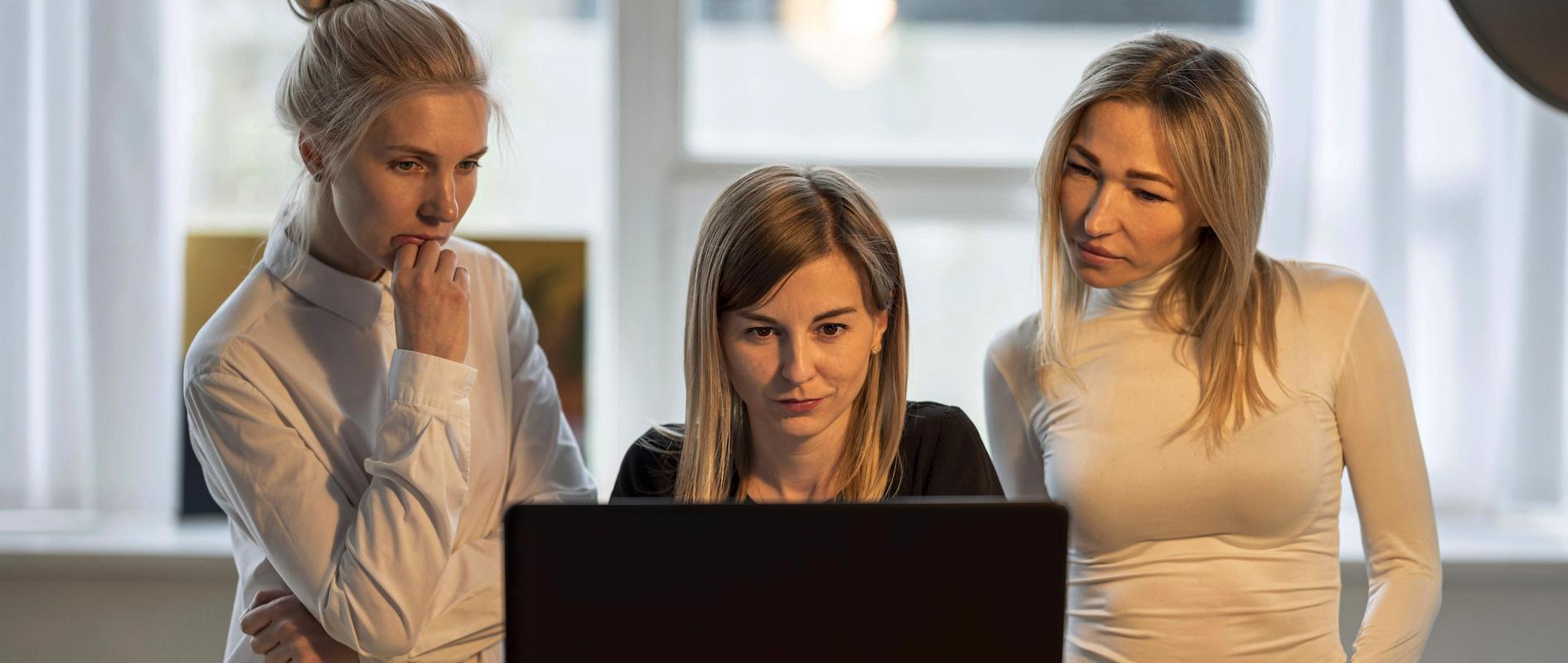 Drei Frauen stehen zusammen vor einem Computer